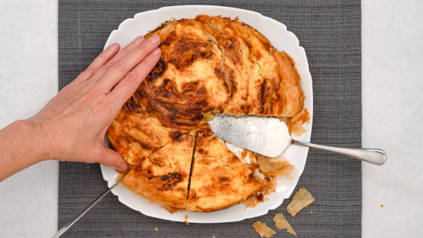 istock Chef delicately slices through a freshly baked phyllo dough pie, showcasing its golden crust and a cream cheese filling 2178548581