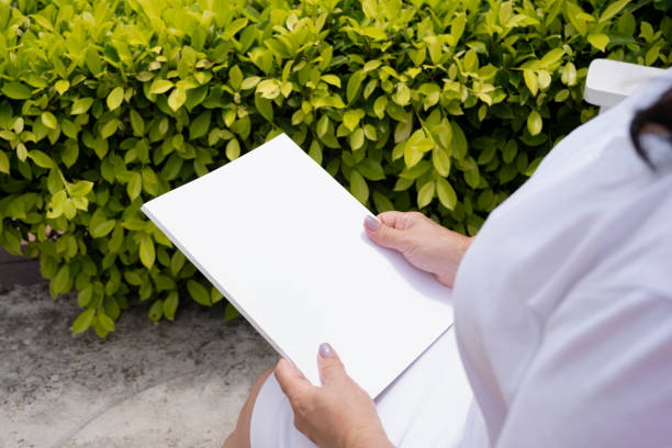 istock unrecognizable woman holding blank magazine for mockup design, sitting on bench 2178551320