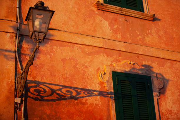 Various views of Idyllic Italian village buildings sunlight ancient stone houses old institutions palaces churches street intertwined and lit this evening by golden hour sunshine low sunset sun, some hard light contrasts with deep shadows, raw stone and umber and sienna lime renders with wrought iron railings the streetlights just switching on