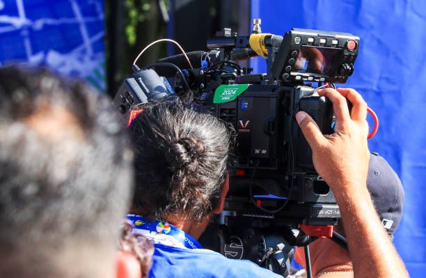 Queens, New York, USA - 20 August 2024: A camera operator focuses intently on filming an outdoor festival with colorful decorations.