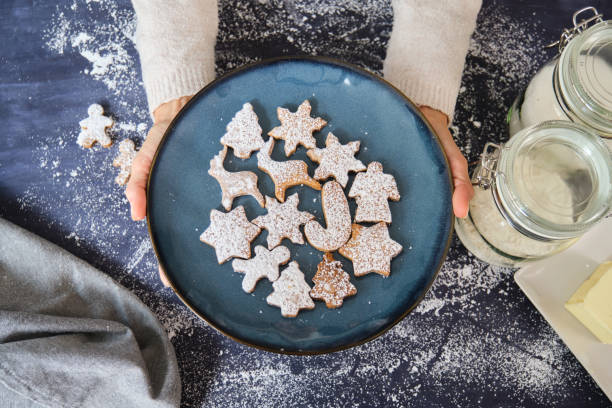 Baker holding plate of Christmas cookies after baking