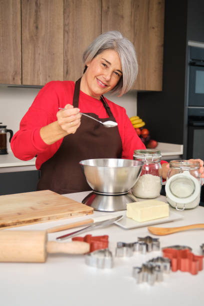 istock Senior woman adding sugar in bowl while baking Christmas cookies 2178552476