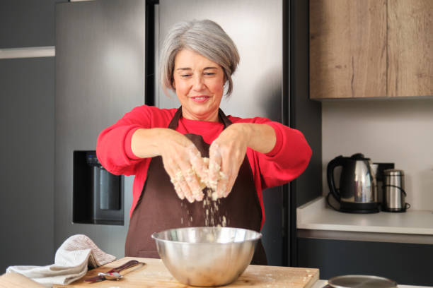 istock Smiling woman adding ingredients to bowl while baking Christmas cookies 2178552751