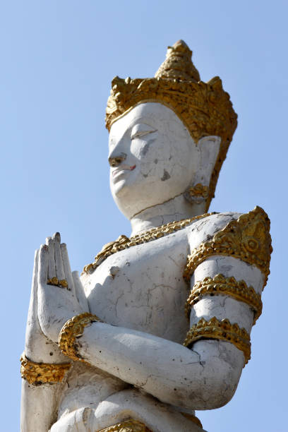 istock CU low angle kneeling white and gold Thai Buddha in profile with blue sky at Wat Inthakin, in Chiang Mai, Thailand 2178553693
