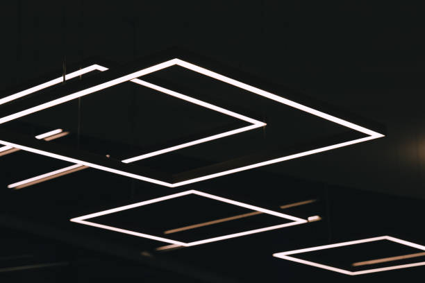 Geometric light fixtures illuminate the ceiling of a modern building stock photo