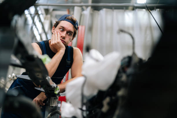 istock Frustrated mechanic male in uniform with thoughtful expression leaning on car part, contemplating best way to approach complex engine repair in garage car service. 2178564923