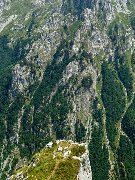 istock Steep mountain cliffs with rocky formations and green forest cover below 2178576519
