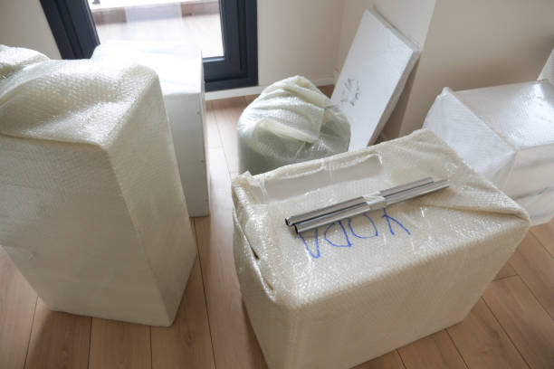 A collection of various covered moving boxes and pieces of furniture situated in a vacant room