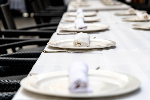 Table arrangement before dinner at a luxury restaurant. Waiters' service preparations. White tablecloths. Design of plates, forks and knives. Celebration dinner, lunch. Restaurant with Bosphorus view. Elegant dining table. Dinner chair.