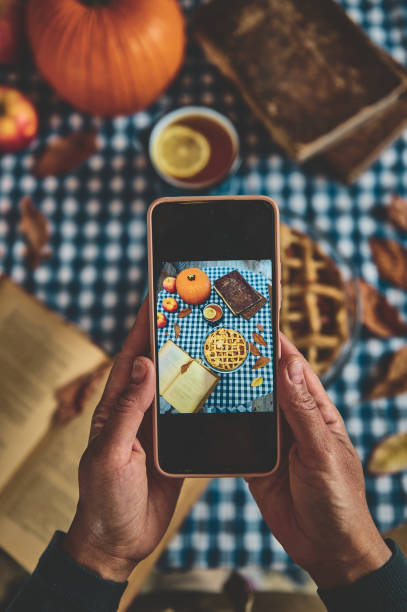 istock Capturing a cozy autumn scene with smartphone showing pumpkin pie on checkered tablecloth, surrounded by seasonal decor 2178580881