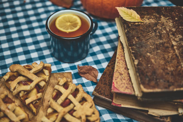 istock Rustic autumn scene with vintage books, warm tea, and apple pie slices on a checkered tablecloth 2178580928