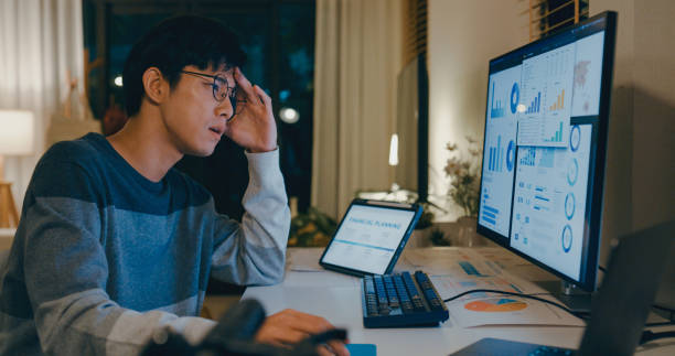 istock Young Asian man tired employee feeling mental burnout while working late at home office, overwhelmed by financial planning and data analysis tasks on multiple screens. Remotely and finance. 2178583007