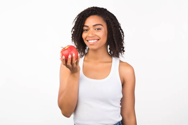 istock Cheerful afro woman holding apple looking at camera 2178584077