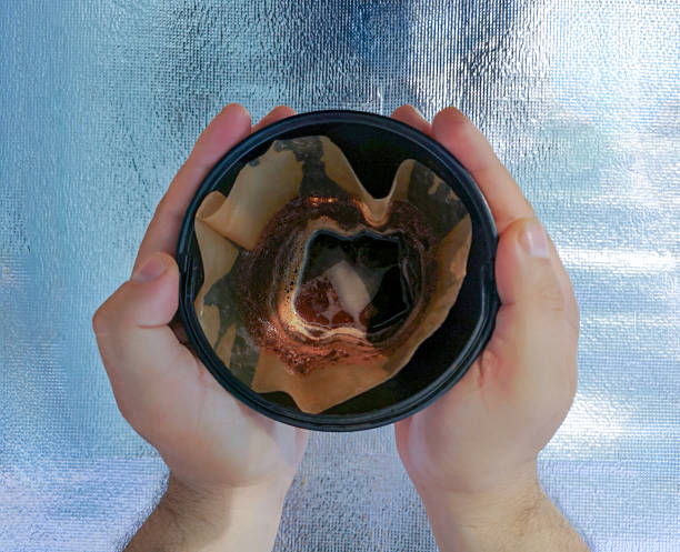 Hands holding a coffee filter with brewed grounds inside