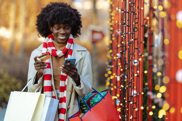 Joyful woman shopping online using mobile phone during holiday season