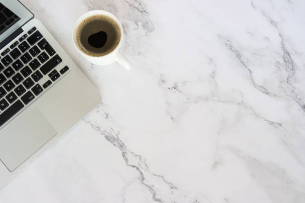 istock Image of office work station with laptop computer by full coffee cup with black coffee, white marble background, elevated view, copy space, home working and coffee break concept 2178595753