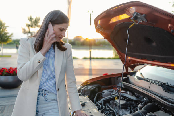 istock Young woman calling for roadside assistance with broken down car 2178597206