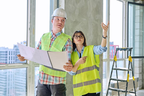 istock Colleagues in protective vest helmet working together on new construction site 2178597442