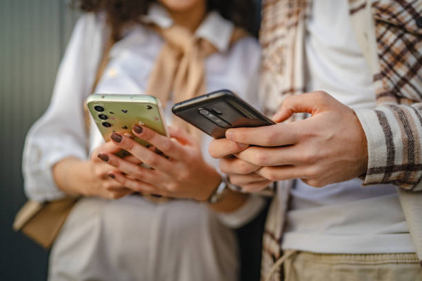 istock Close up of young couple use cellphone in front black wall 2178599269