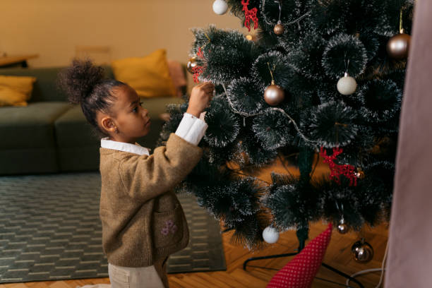 istock Small girl hangs ornaments on the Christmas tree 2178600385
