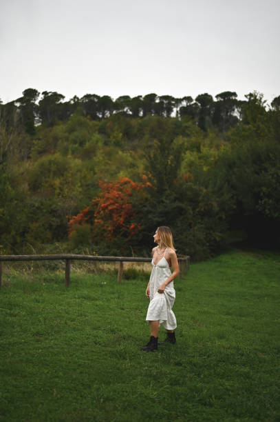 Young woman walking in nature with evergreen trees. Young woman walking in the mountains and looking around in the woods. Happy girl walking in the woods. Happy girl walking in nature.
