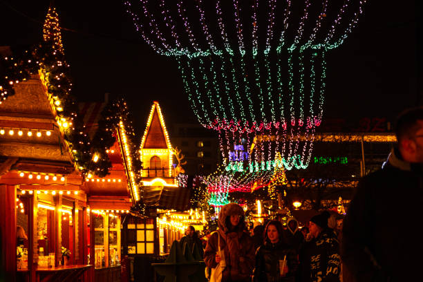 Berlin, Germany, January 5th, 2024. Christmas market in Berlin illuminated by dazzling light displays. People are walking, enjoying seasonal food and drinks, and gifts shopping in festive booths.