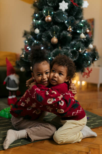 istock Brother and sister in matching christmas sweaters hugging by tree 2178604050