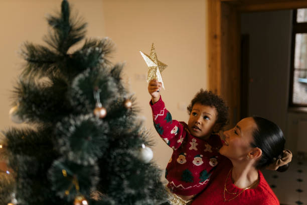 istock Family decorating christmas tree with mother helping son place star 2178604632