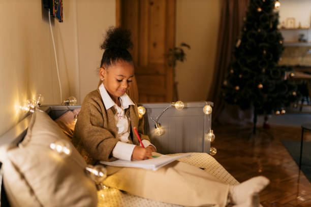 istock Young girl doing drawing on the sofa with Christmas string lights around 2178608331