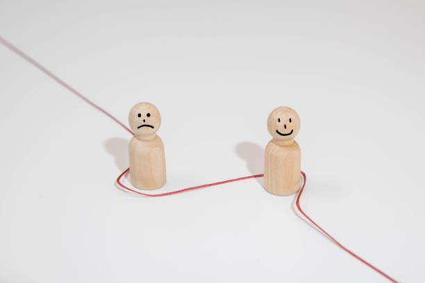 Two wooden drawing mannequins used for drawing reference holding an artist's sketching pencil together on a blank white background with copy space.