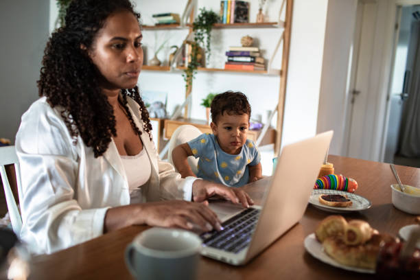 istock Young mother and son having breakfast together while the mother is working on her laptop 2178611269