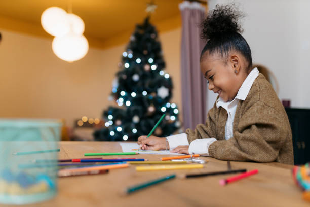 istock Smiling little girl drawing with christmas tree in background 2178614012
