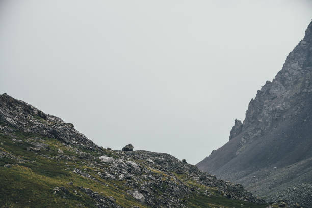 istock Atmospheric highlands landscape with narrow mountain valley and sharp rocks on steep slope under gray sky. Bleak mountain scenery with pointed rockies on mountainside and glen in overcast weather. 2178617085