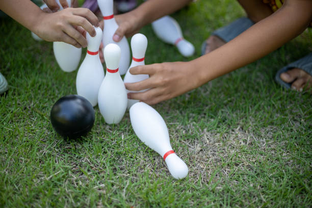 Children's hands helping to set up a bowling pins