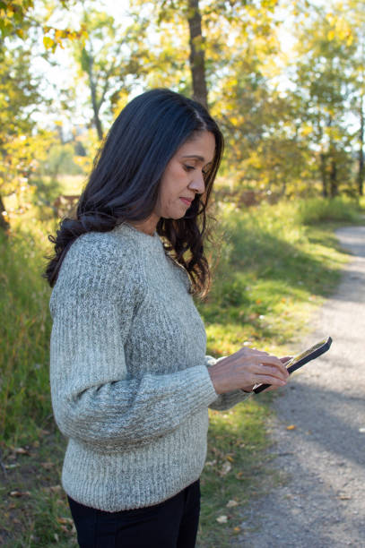 istock Woman Engaged with Her Phone in the Park 2178630807