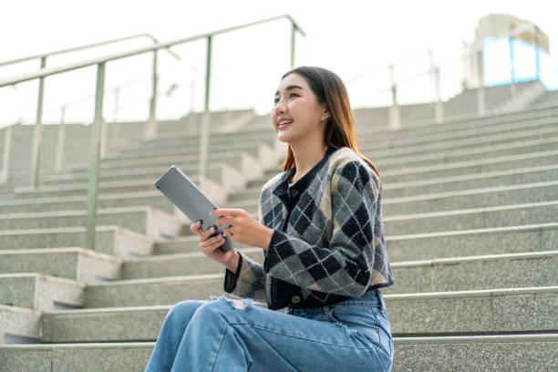 istock Gen Z Young Woman Using Digital Tablet Outdoors, Looking Away Contentedly 2178636519
