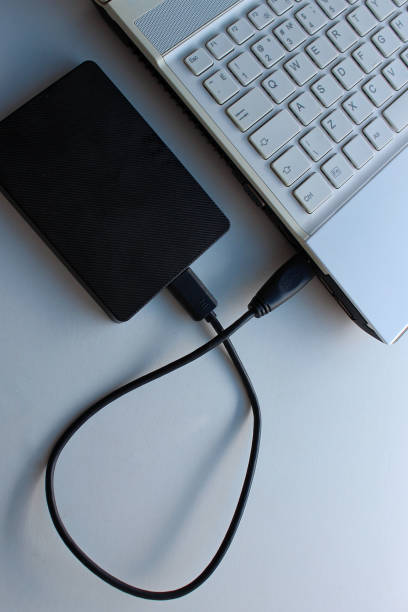 istock Black cable connects a compact laptop and portable hard disk isolated on white 2178647321