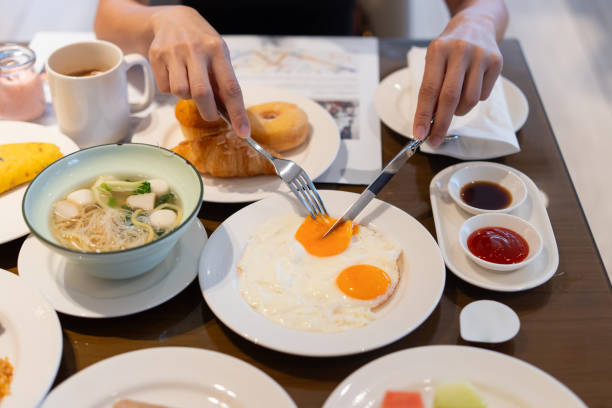 istock Woman's hand using utensils to cut into the yolk of a sunny-side-up egg. 2178650353