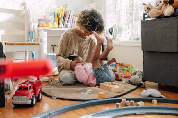 Cozy life, young mother with her little girl playing at home.