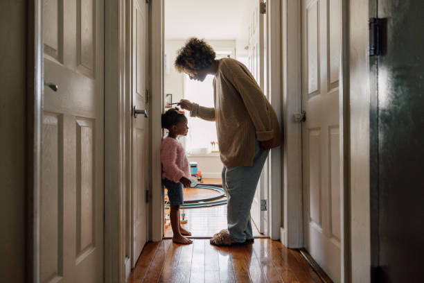 istock Mother measuring daughter's height and marking on wall at home 2178660514