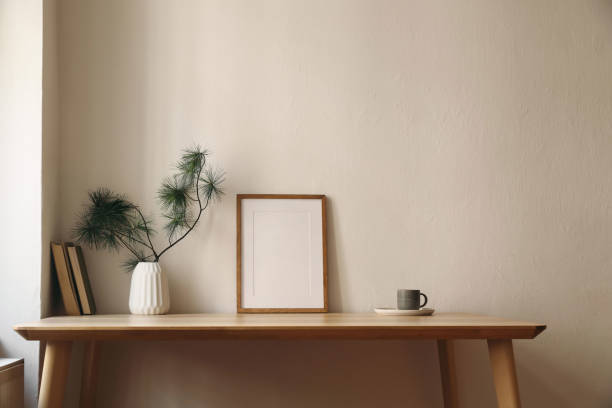 istock Elegant Christmas interior. Winter home still life. Scandinavian decor. Blank vertical thin picture frame mockup, cup of coffee tea. Wooden desk, table. Pine tree branches, vase. Beige wall background 2178663040