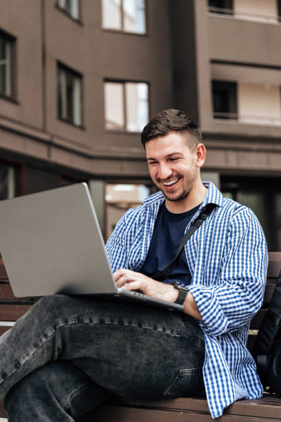 istock Young man working on a laptop while seated on a bench outside 2178665699