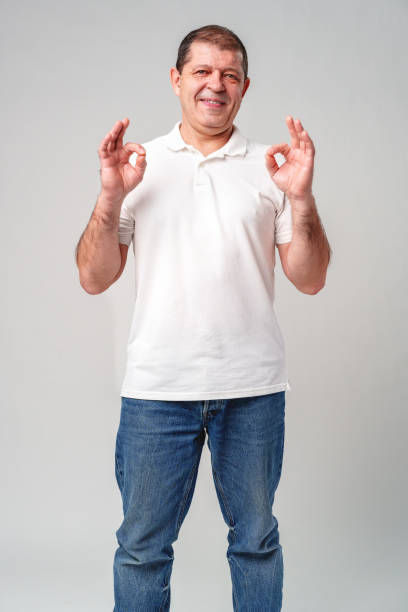 istock A man in a white shirt poses with a cheerful expression showing OK hand gestures in a well-lit indoor setting 2178665920