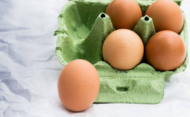 istock Green egg carton with four brown eggs and one egg outside, copy space. 2178666075