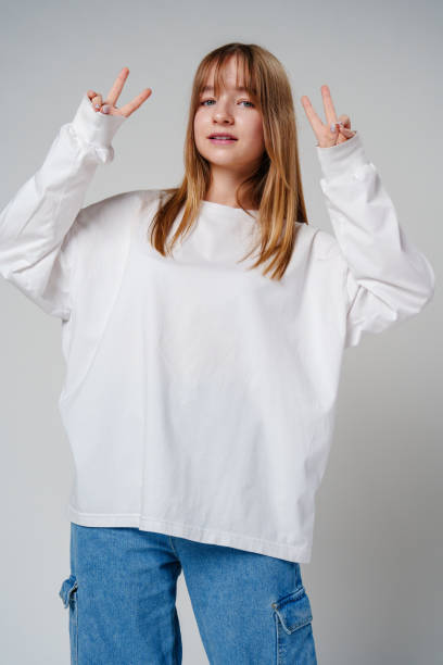 istock Young woman joyfully posing with peace signs against a plain background 2178666922