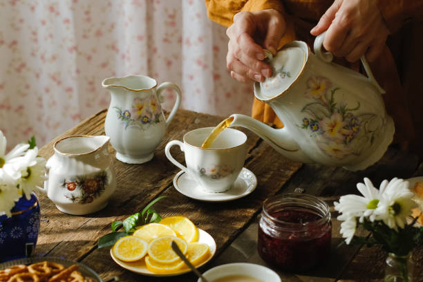 istock Tea party in rustic style. Pouring tea from teapot into porcelain cup. 2178669835