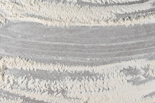 Grey cooking background of spilled wheat flour on stone background, top view