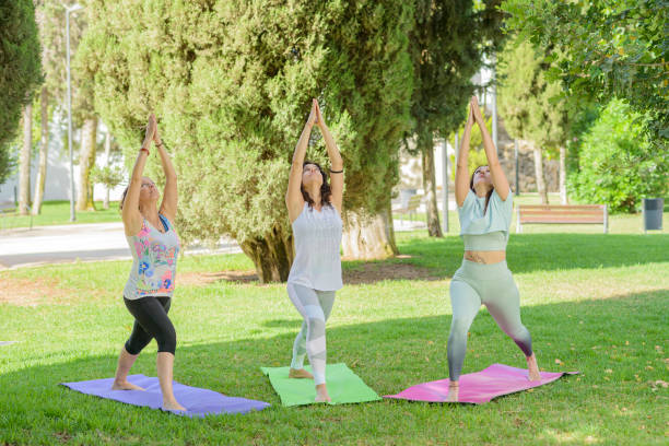 istock Three women practicing yoga in a public park. 2178675727