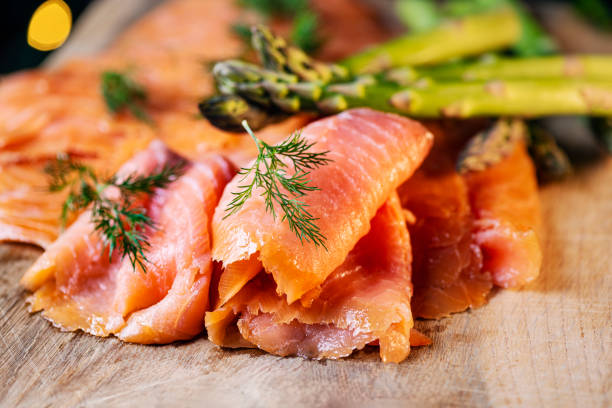 Close-up shot of smoked salmon served with dill and asparagus.