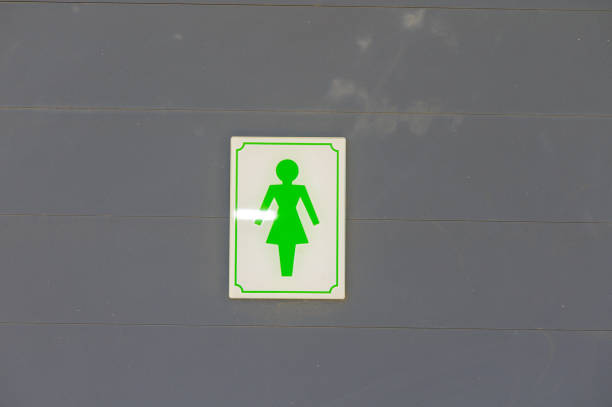 The vibrant green sign indicating a women\\'s restroom contrasts sharply with the gray background, drawing attention to the importance of accessible facilities in urban settings.